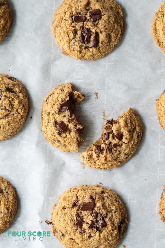 top down view of Low Carb Keto Chocolate Chip cookie on a baking sheet, one cookie is broke in half