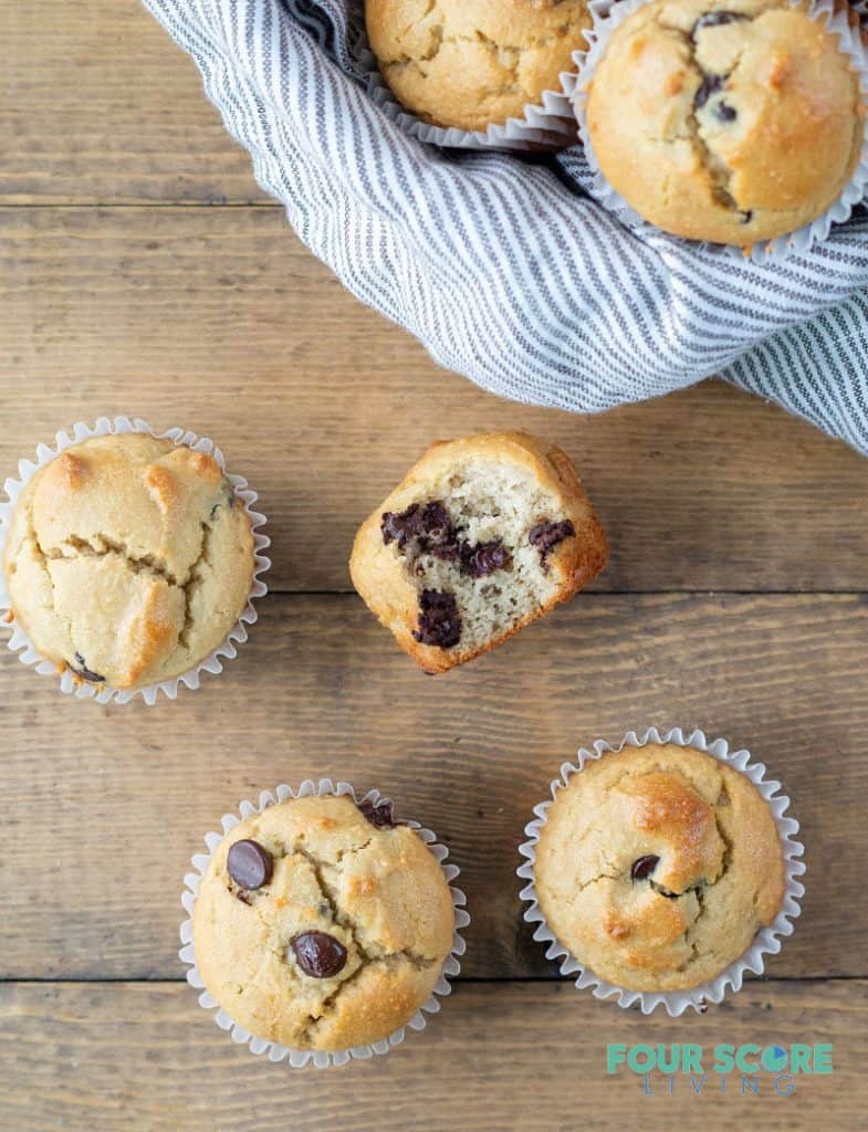 Low Carb Chocolate Chip Muffins on a wood background, one has a bite out to show the texture