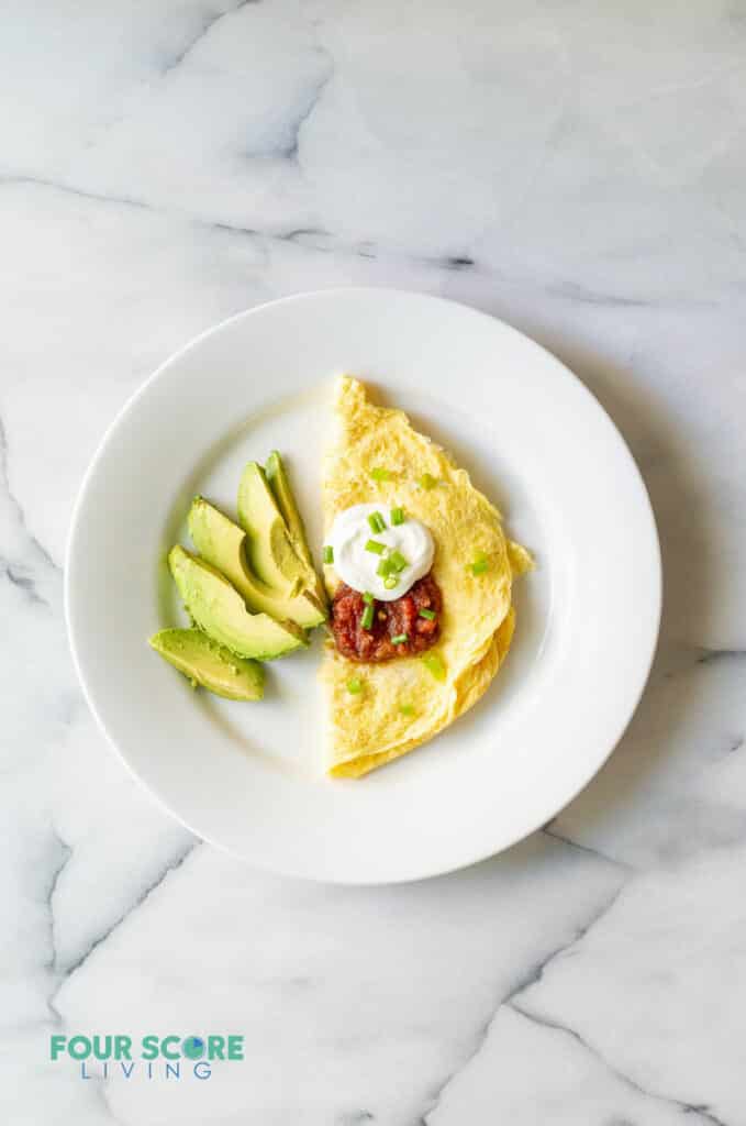 cooked scrambled ggs and sliced avocado on a white plate