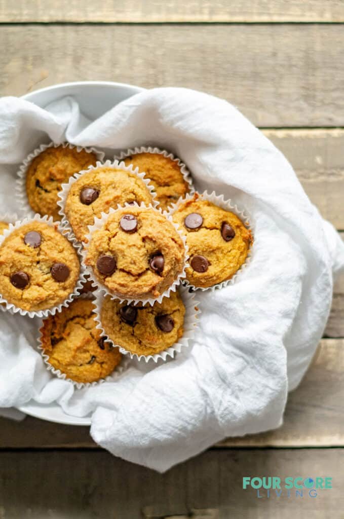 low carb pumpkin muffins with chocolate chips on a white dish towel in a bowl