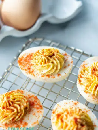 a close up of keto deviled eggs on a wire rack with paprika on top