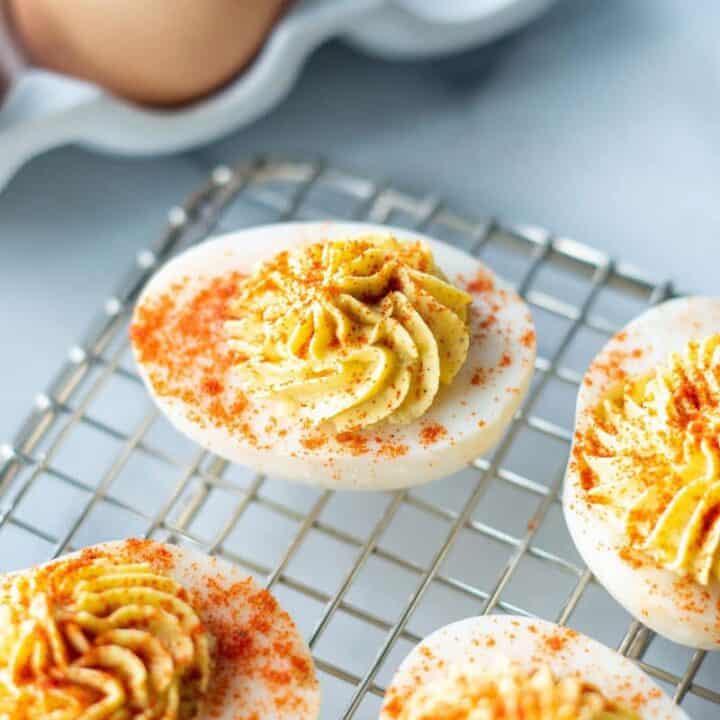 a close up of keto deviled eggs on a wire rack with paprika on top