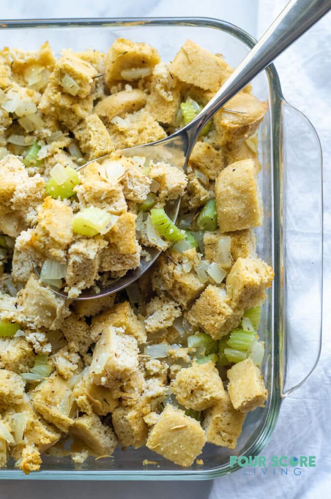 keto stuffing in a glass pan with a spoon getting a spoonfull of stuffing