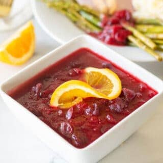 keto cranberry sauce in a white bowl with a orange slice