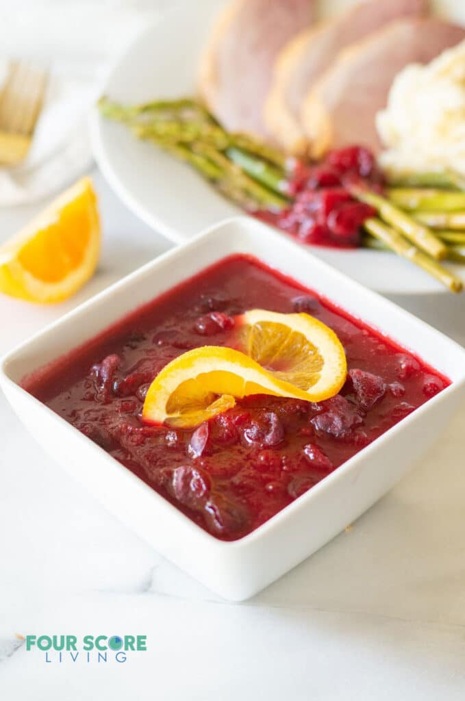 keto cranberry sauce in a white bowl with a orange slice