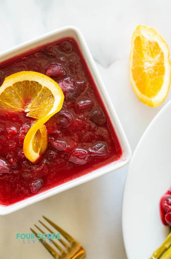 keto cranberry sauce in a white bowl with a orange slice