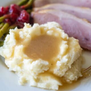 keto gravy over mashed cauliflower on a plate with ham