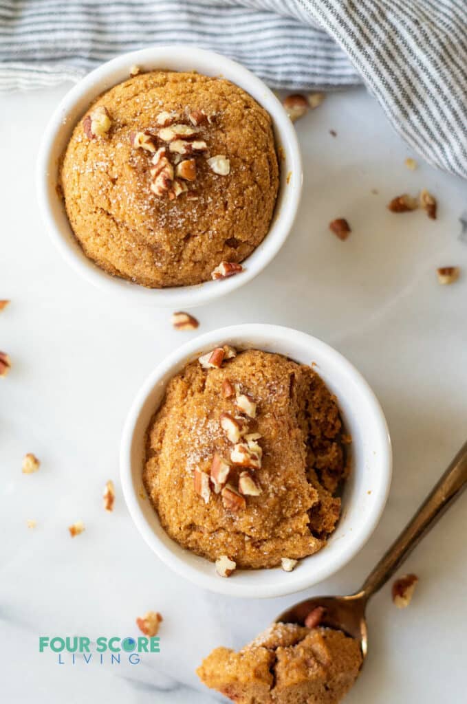 two keto pumpkin mug cakes with a golden spoon