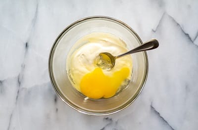Top view photo of a glass bowl with egg added to the cheese mixture to make Keto Rolls.