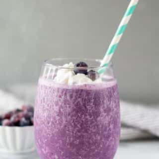 side view of keto berry smoothie in a glass with a straw