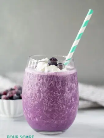 side view of keto berry smoothie in a glass with a straw