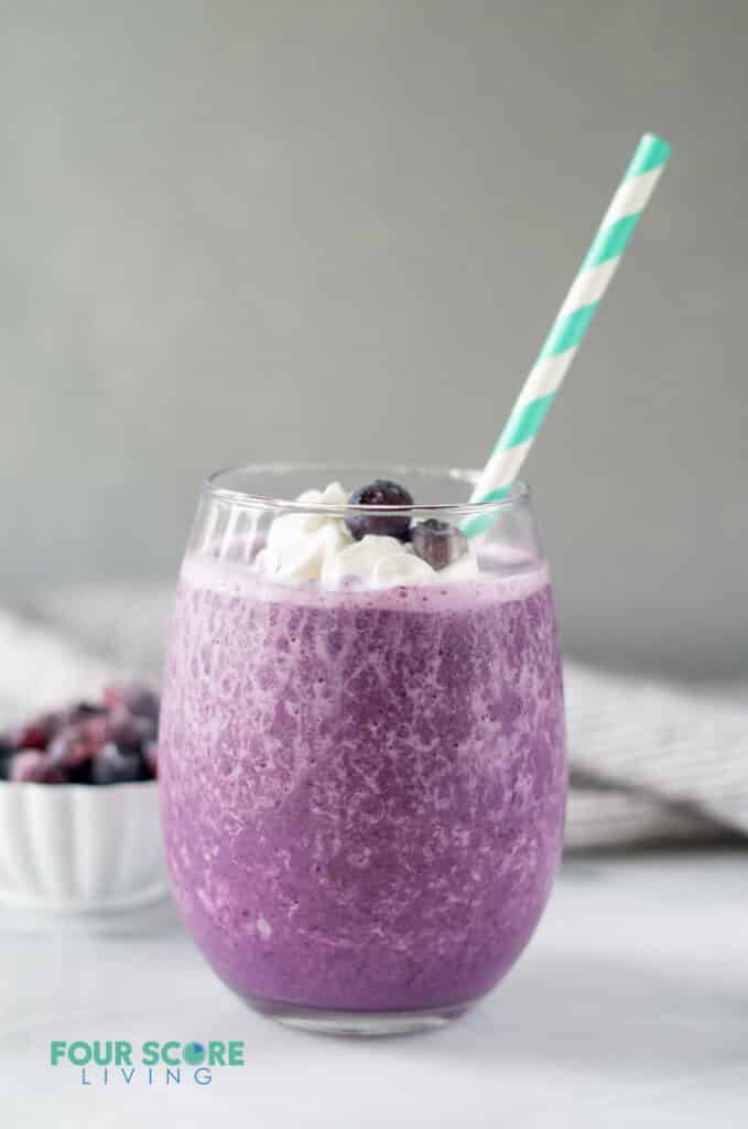 side view of keto berry smoothie in a glass with a straw