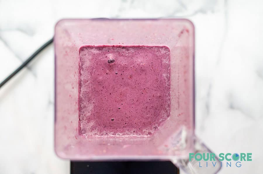 a blender filled with a freshly blended bright purple colored keto berry smoothie