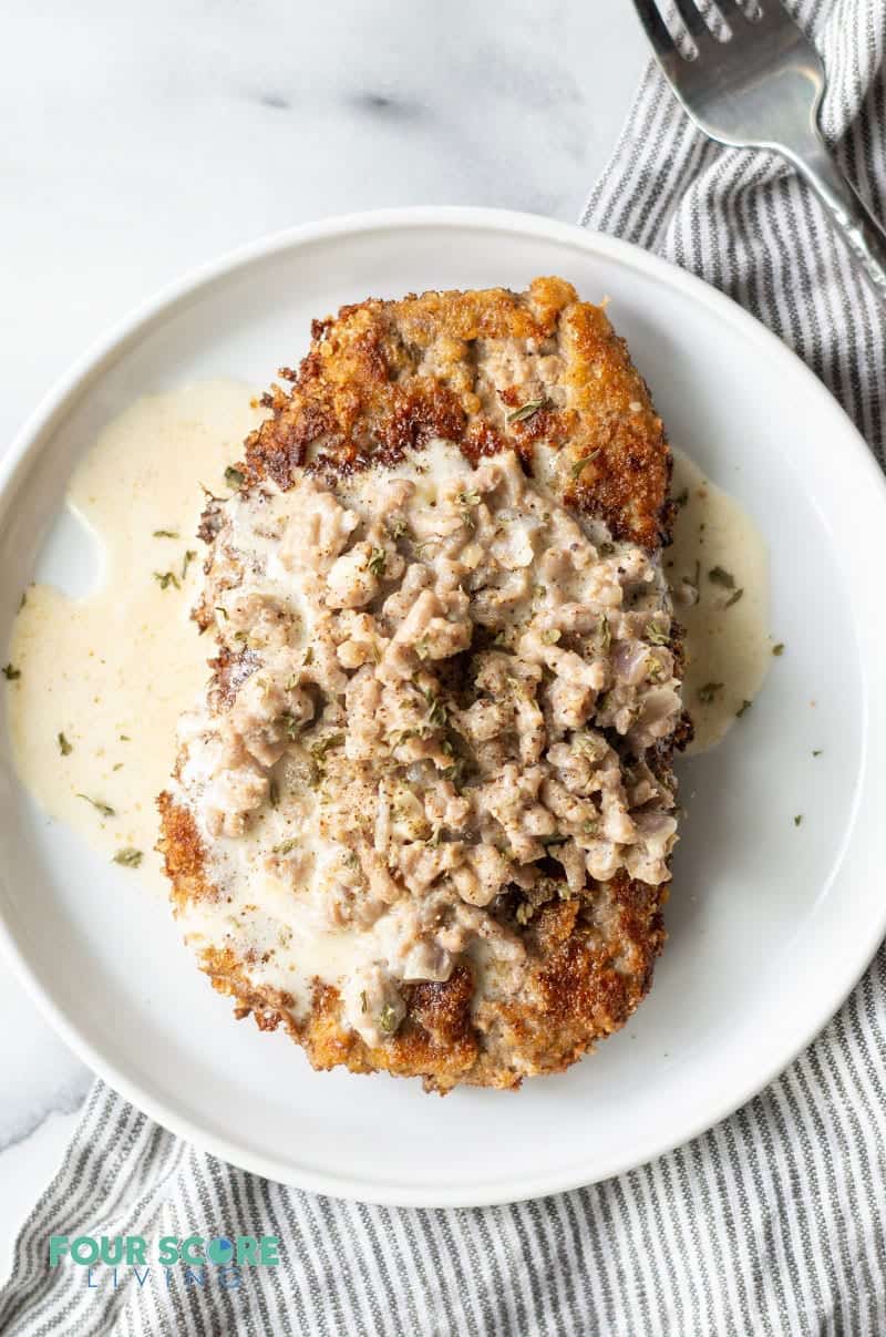 chicken fried steak with gravy on a round white plate