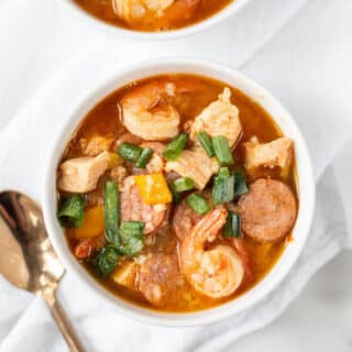 white bowls filled with jambalaya with shrimp, chicken, and sliced sausage