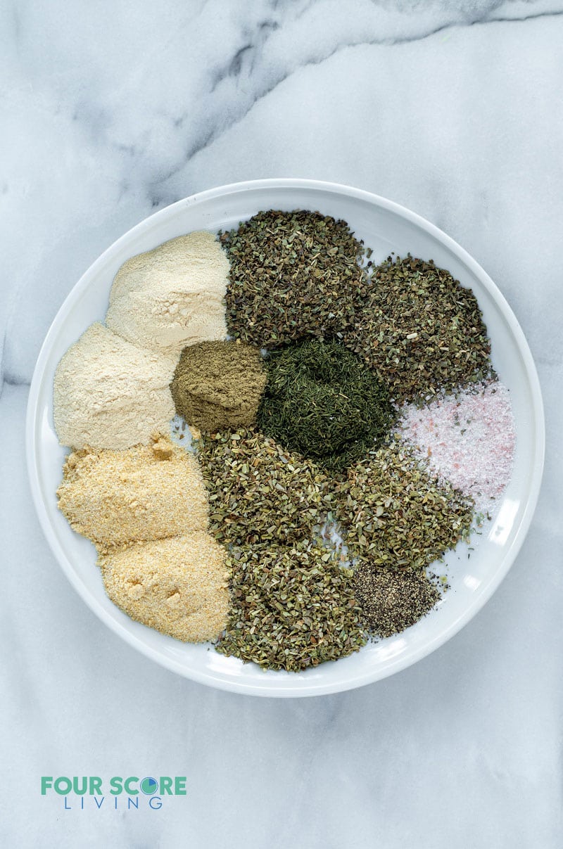 a bowl with individual measurements of green, brown, tan, and white spices.