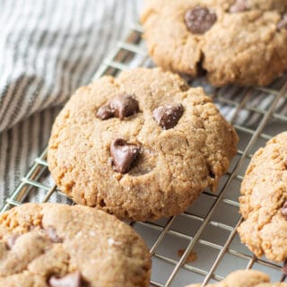 chocolate chip cookies on a wire rack over a striped gray towel