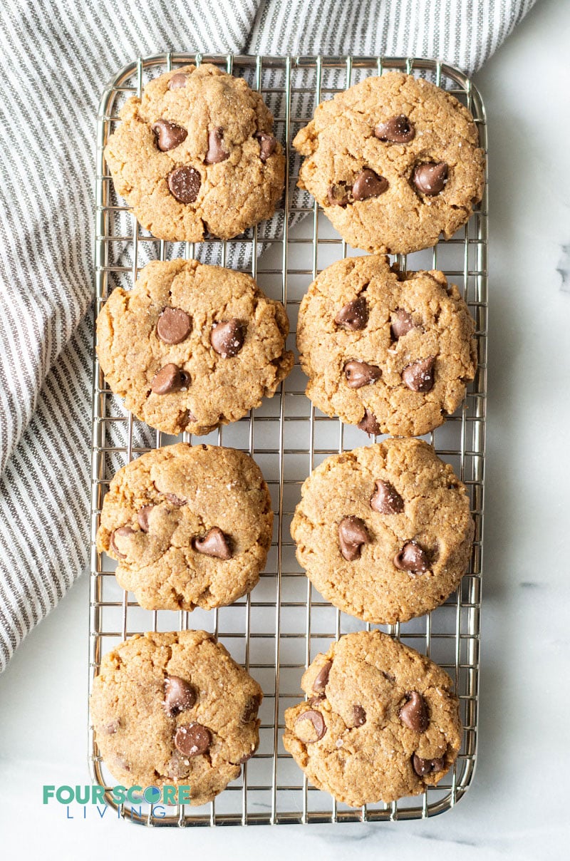 eight brown keto cookies with chocolate morsels cooling on a wire mesh rack