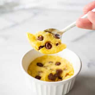 a spoon lifting a scoop of a keto chocolate chip mug cookie out of a white dish