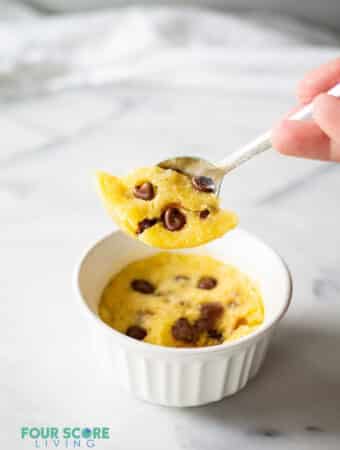 a spoon lifting a scoop of a keto chocolate chip mug cookie out of a white dish