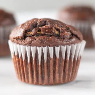 close up of a chocolate zuchinni muffin in a white cupcake liner