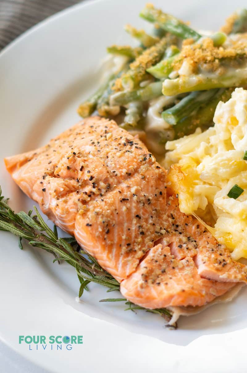 a salmon filet on a plate with cheesy cauliflower and green beans