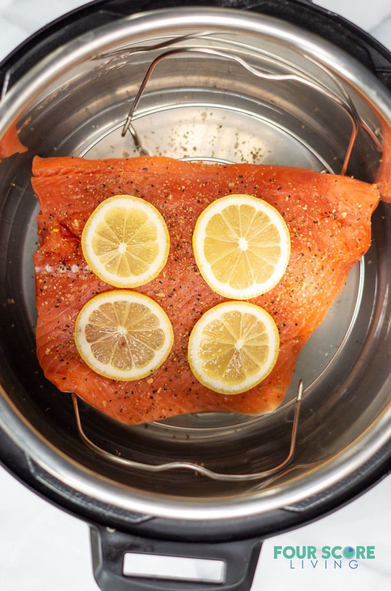 uncooked salmon topped with slices of lemon in the bottom of a pressure cooker