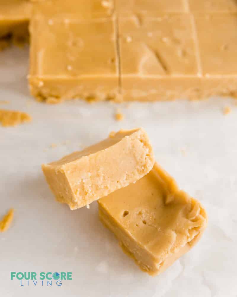 two pieces of keto peanut butter fudge in front of more peanut butter fudge