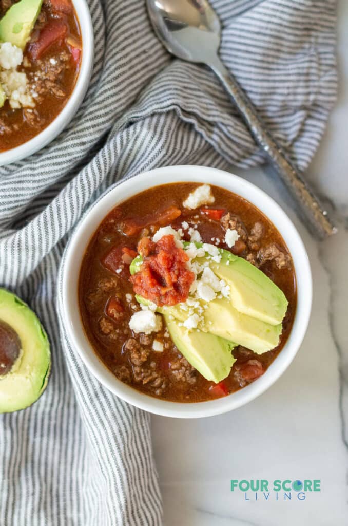 top down view of keto taco soup topped with avocado, salsa, and feta