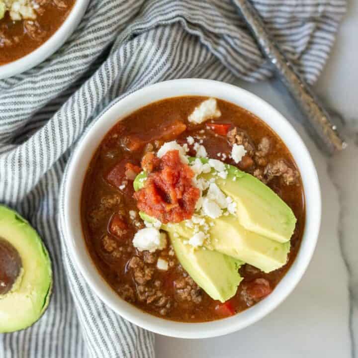 top down view of keto taco soup topped with avocado, salsa, and feta