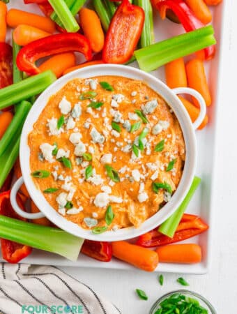 keto buffalo dip in a white bowl topped with blue cheese and onions