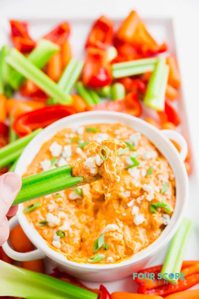 a celery stick being dipped into keto buffalo chicken dip