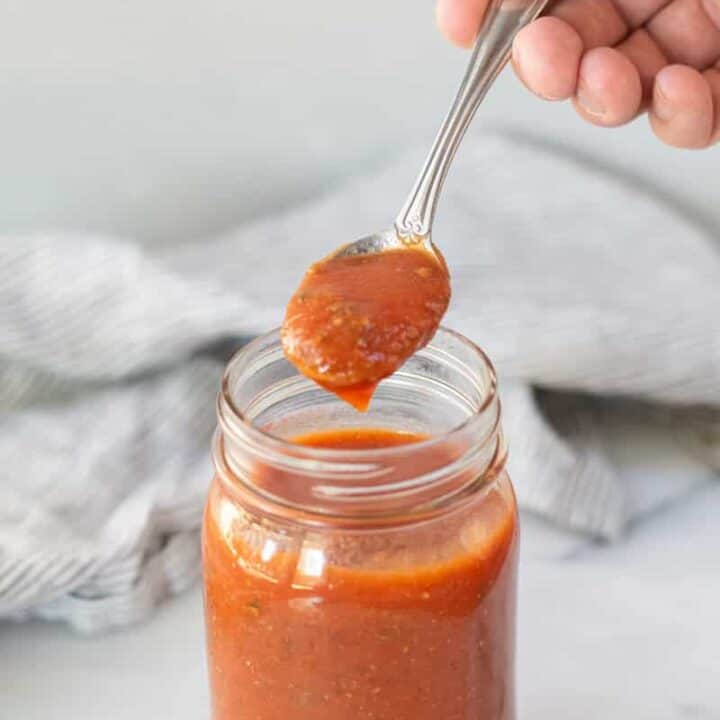 a spoonful of keto pizza sauce over a jar of sauce