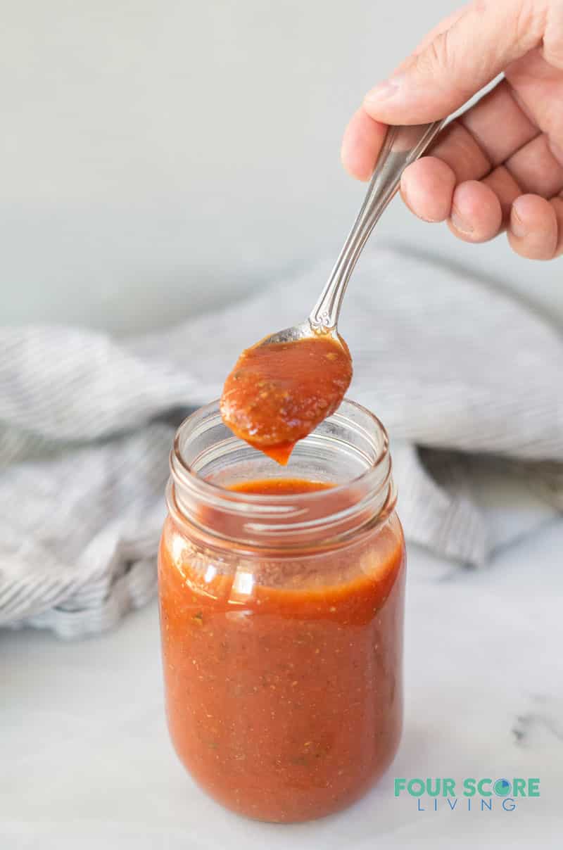 a spoonful of keto pizza sauce over a jar of sauce
