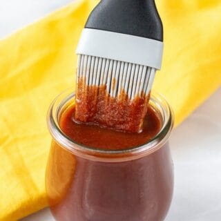 BBQ sauce in a small glass jar with a basting brush in it