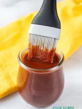 BBQ sauce in a small glass jar with a basting brush in it