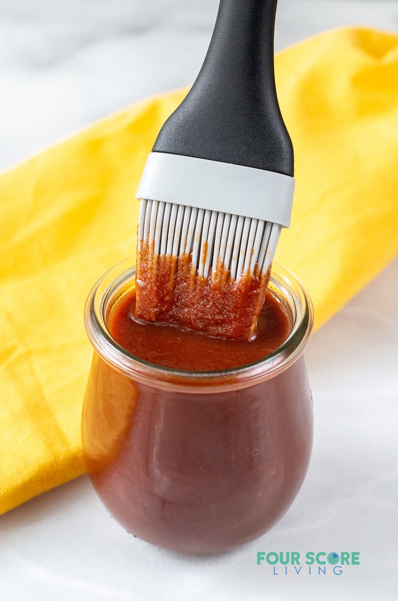 keto BBQ sauce in a small glass jar with a basting brush in it