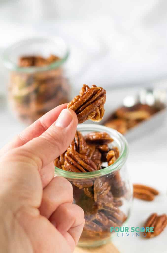 a hand holding a keto candied pecan