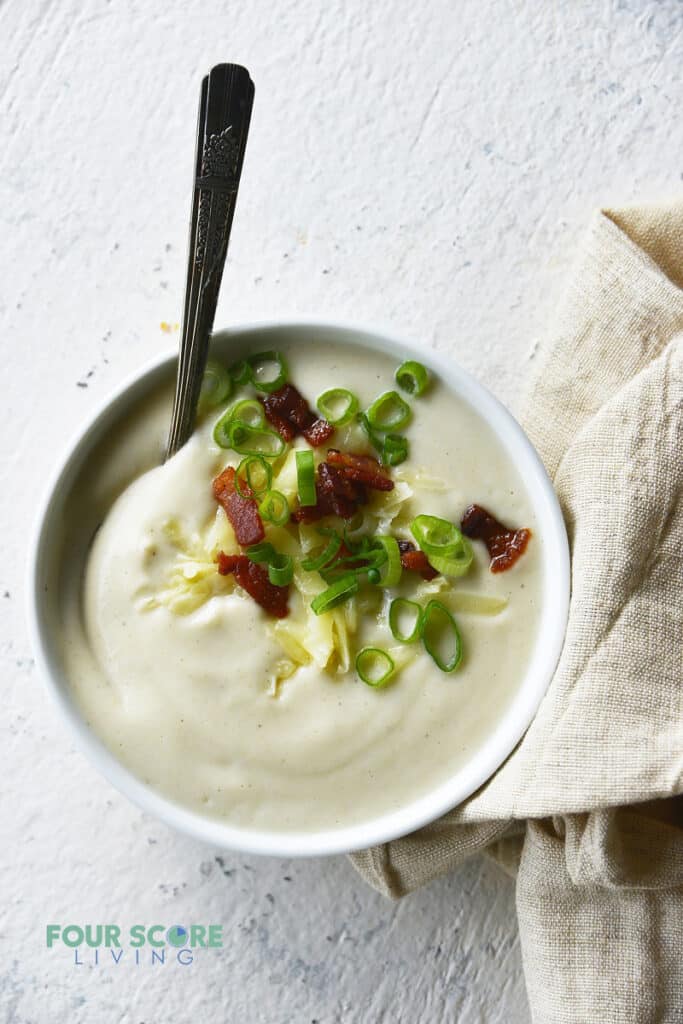 A bowl of creamy cauliflower soup topped with bacon and green onion