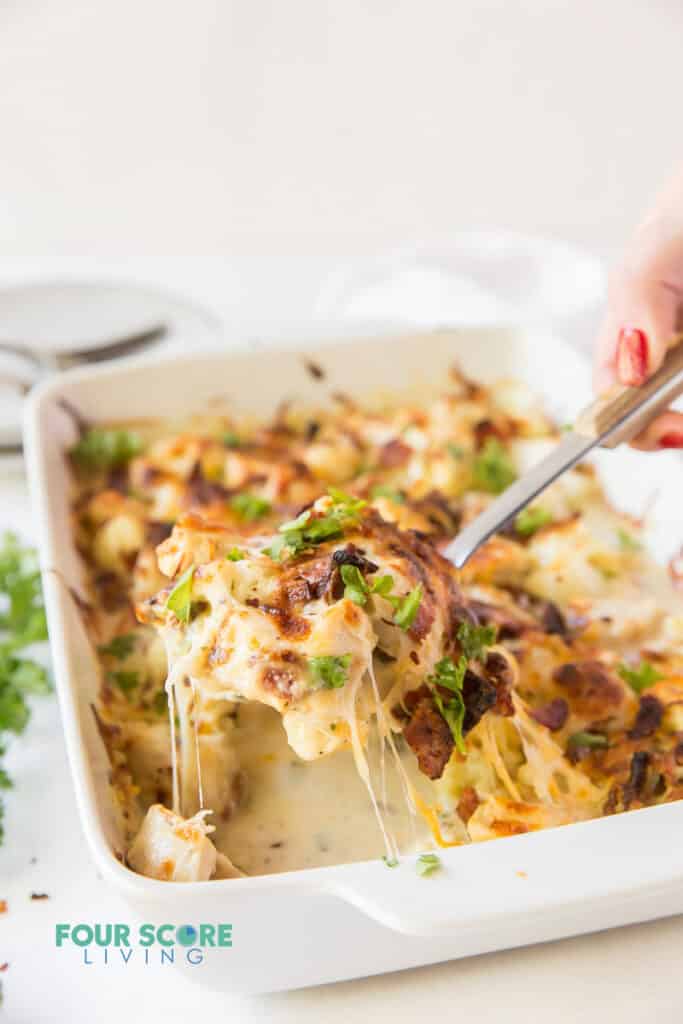 Chicken bacon ranch casserole being served out of a white baking dish. 