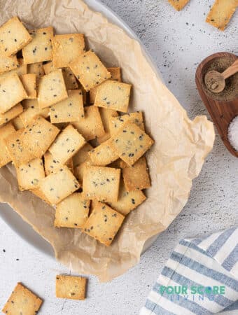 An oval dish lined with paper with square crackers inside.