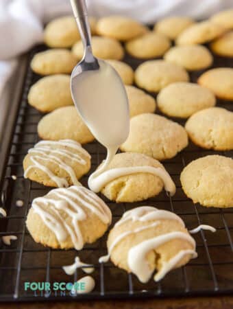 cookies on a tray being drizzled with white glaze.