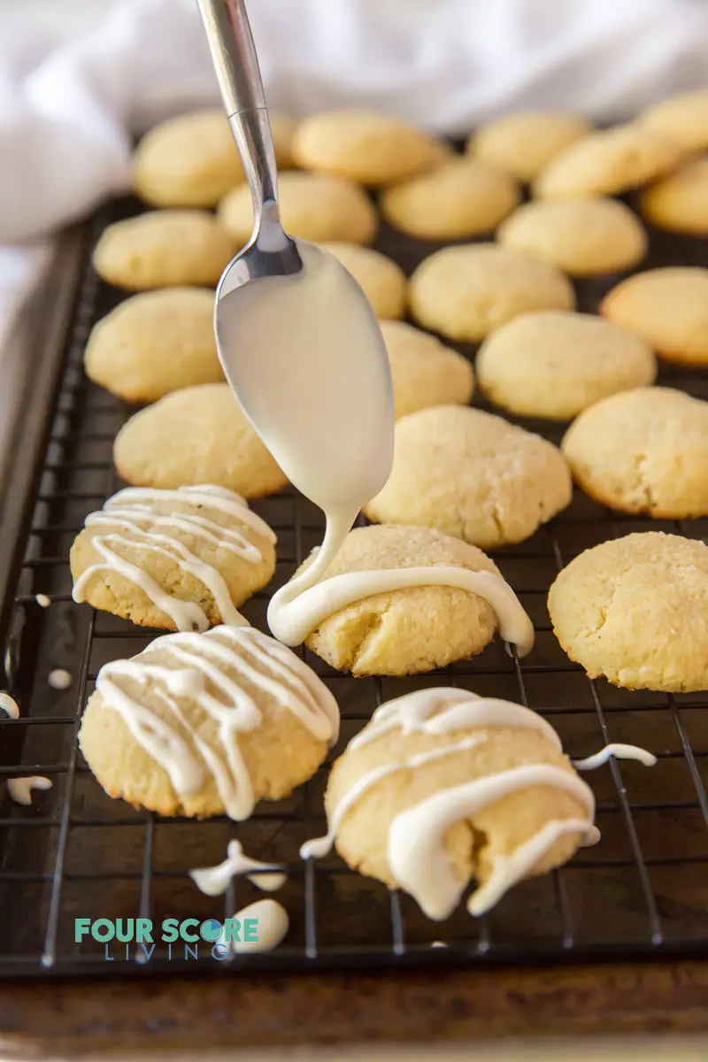 cookies on a cooling rack being drizzled with white glaze.
