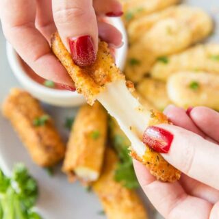 a mozzarella stick being pulled apart to show the cheese inside.