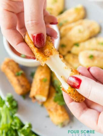 a mozzarella stick being pulled apart to show the cheese inside.