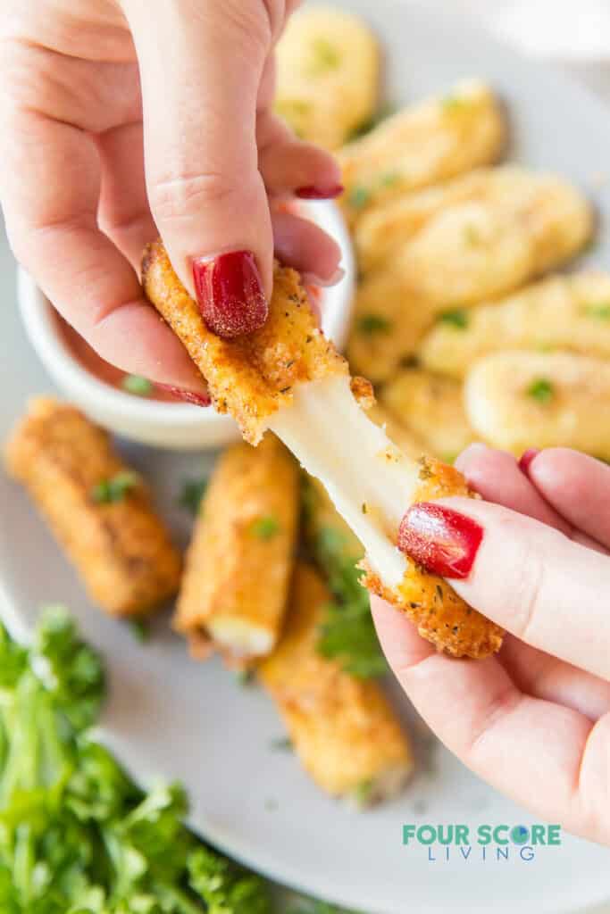 a mozzarella stick being pulled apart to show the cheese inside.