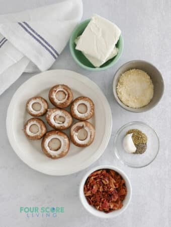 Top down view of ingredients for stuffed mushrooms, including mushroom caps, bacon, cheese, and seasonings.