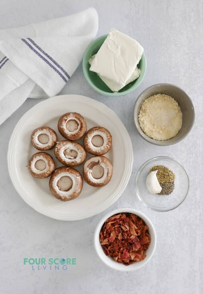 Top down view of ingredients for stuffed mushrooms, including mushroom caps, bacon, cheese, and seasonings.