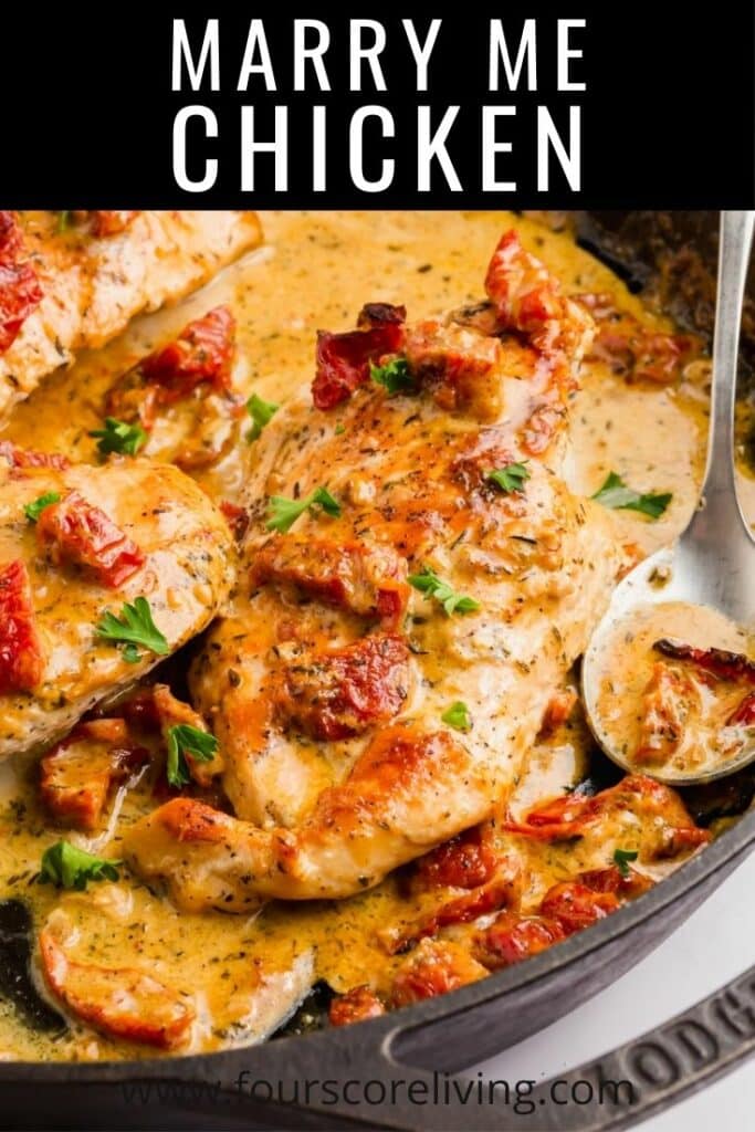 A cast iron skillet filled with chicken in a creamy sauce toped with sundried tomatoes and parsley, with the title, Marry Me Chicken.