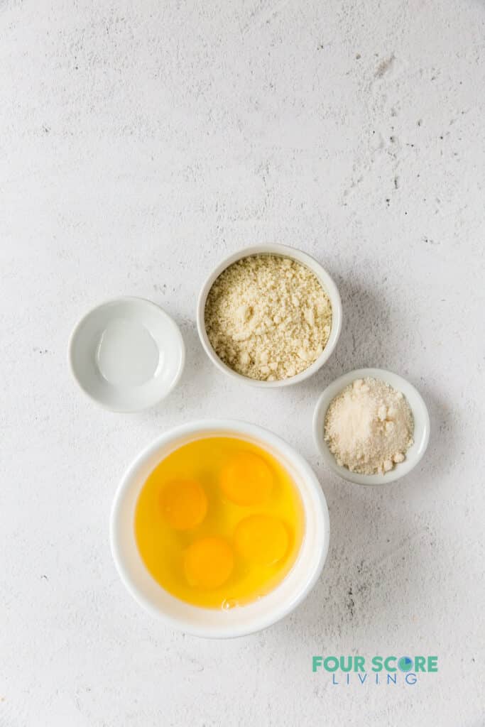 4 small bowls with the ingredients needed for crepes including flour, sweetener, and eggs.